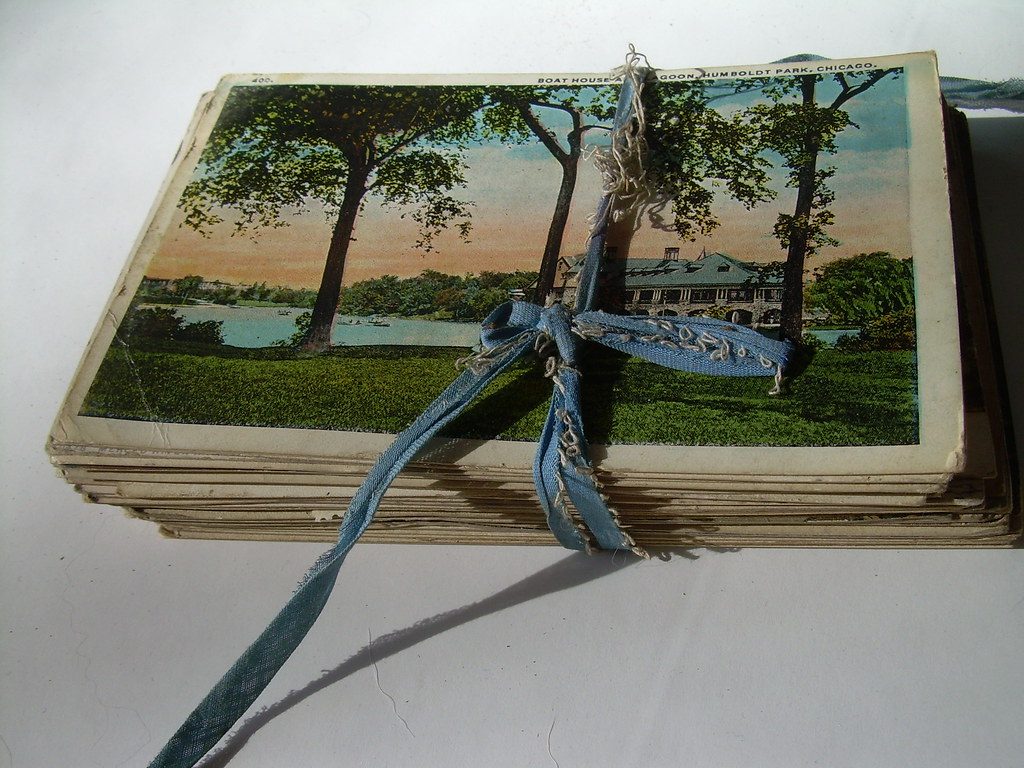 A stack of old postcards tied together with a faded blue ribbon.