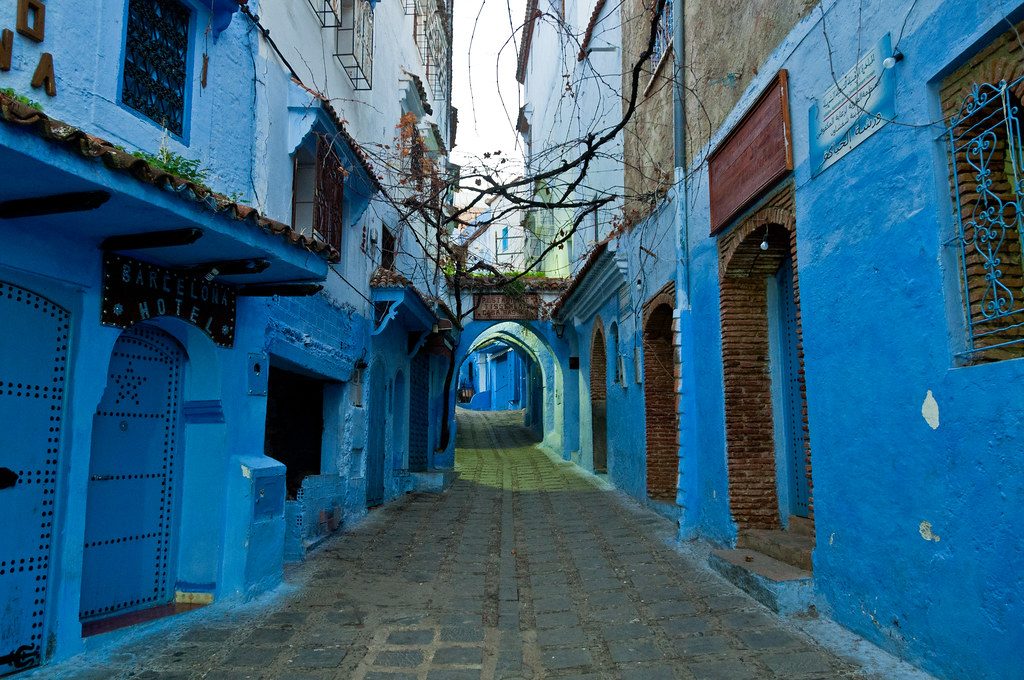 A narrow street in Chefchaouen, Morocco, with every wall painted a deep blue.