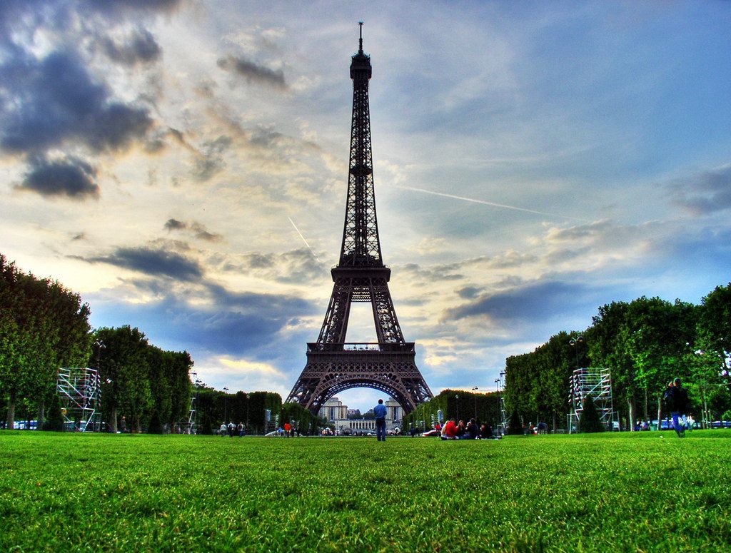 The Eiffel Tower in Paris under a dramatic cloudy sky.