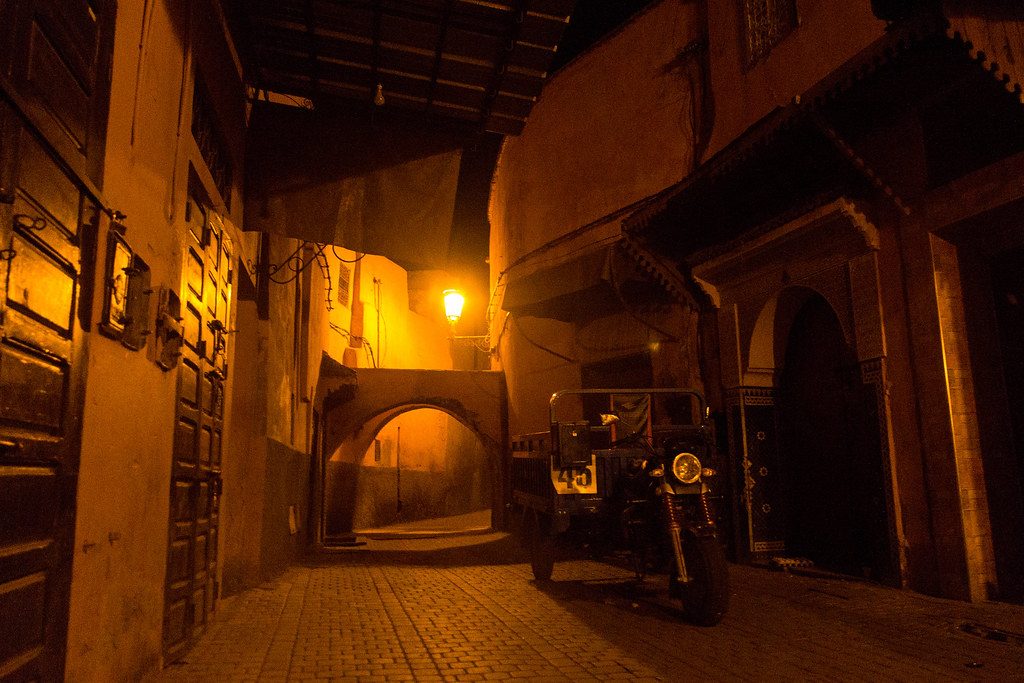 A dimly lit covered alley in the medina of Marrakech at night.