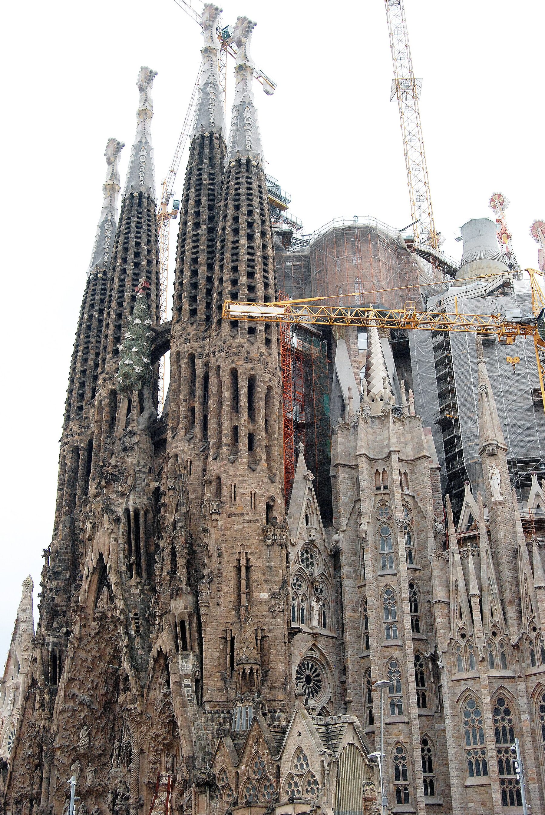 The spires and carved facade of the Sagrada Familia in Barcelona, with construction cranes.